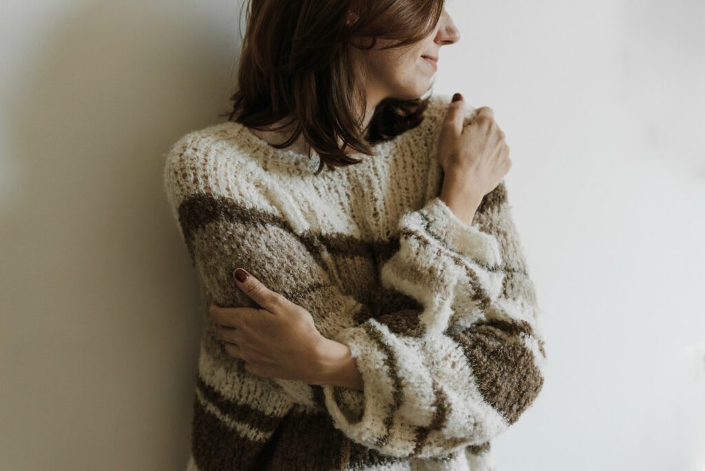 A Woman in Knit Sweater Hugging Self