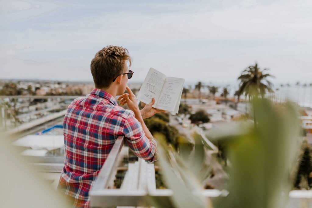 hombre leyendo un libro en el balcon durante el dia