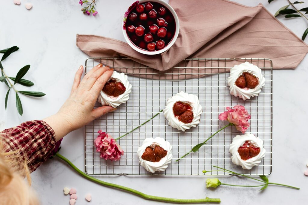 persona sosteniendo un plato de cerámica blanca con flores rojas y blancas